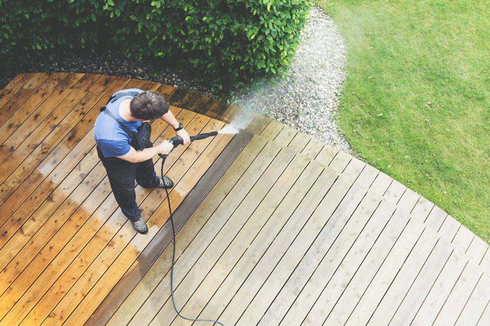 man pressure washes his deck